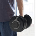 Person holding a pair of adjustable dumbbells with a blurred background