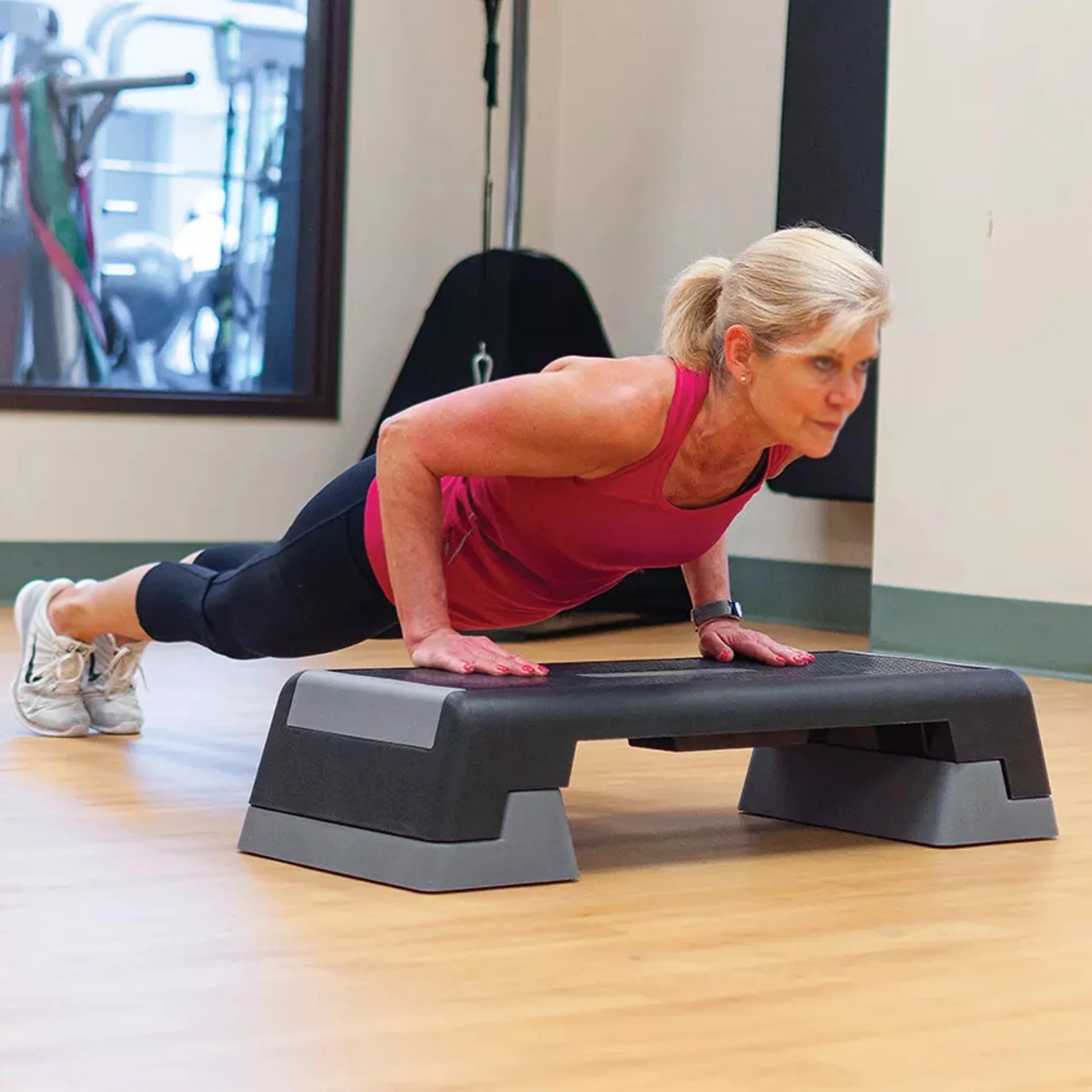 Woman exercising on an step platform in a gym setting