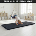 Child playing on a black 'Fun & Flip Kids Mat' in a bright room with toys and furniture.