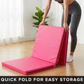 Person folding a pink mat with text 'Quick fold for easy storage' in a room with a plant.